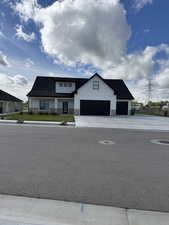 Modern farmhouse style home featuring board and batten siding, stone siding, and driveway
