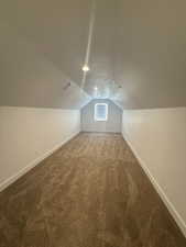 Bonus room with baseboards and dark carpet