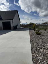 View of home's exterior featuring stone siding, driveway, an attached garage, and roof with shingles