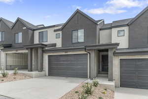 View of front facade with stucco siding, stone siding, a garage, and concrete driveway