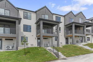 Modern home with stucco siding, a front yard, and a balcony
