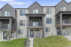 View of front of home featuring stucco siding, a patio area, and a front yard