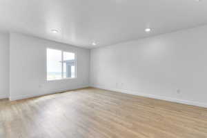 Spare room featuring light wood-type flooring, a textured ceiling, and recessed lighting