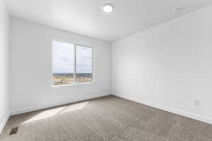 Carpeted spare room featuring baseboards