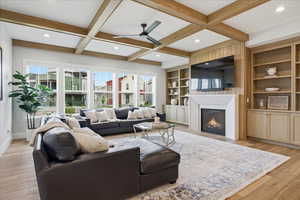 Living area featuring a ceiling fan, a lit fireplace, light wood floors, recessed lighting, and built in shelves
