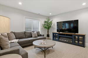 Carpeted living area with recessed lighting and baseboards