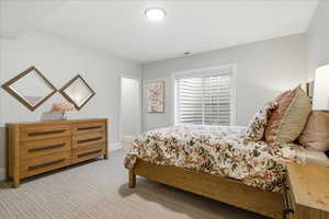 Bedroom featuring light colored carpet and baseboards with on suite bathroom