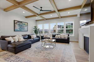 Living room featuring a ceiling fan, light wood flooring, a fireplace, recessed lighting, and coffered ceiling