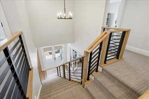 Stairway featuring carpet, hanging lights, and a high ceiling