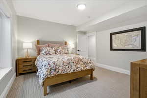 Bedroom featuring light colored carpet and baseboards with on suite bathroom