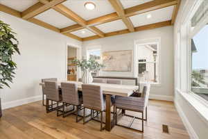Dining area with light wood-style floors, coffered ceiling, and recessed lighting