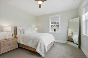 Carpeted bedroom with ceiling fan and baseboards