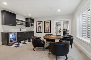 Indoor wet bar featuring wine cooler, dark cabinets, open shelves, light carpet, and recessed lighting