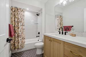 Bathroom featuring vanity, shower / tub combo with curtain, and dark tile patterned flooring