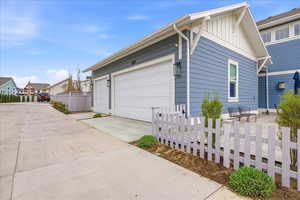 View of side of home with board and batten siding, driveway, a residential view, a patio area, and an attached three car garage