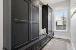 Mudroom featuring cabinets and bench baseboards and light wood flooring