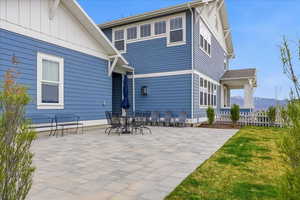 Rear view of house featuring board and batten siding, a large paver patio, outdoor dining space, and a mountain view