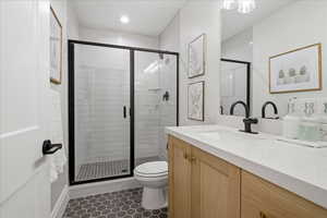 Full bath with a shower stall, vanity, and dark tile patterned floors