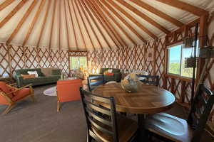 Carpeted dining room with vaulted ceiling with beams