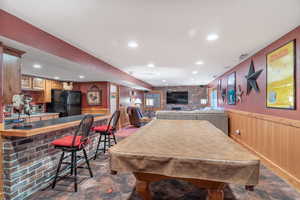 Rec room with wood walls, wainscoting, recessed lighting, billiards, and brick wall