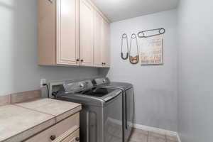 Laundry room featuring cabinet space, washing machine and dryer, and light tile patterned floors
