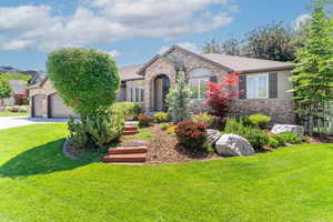 French country home featuring brick siding, a front yard, driveway, and a garage