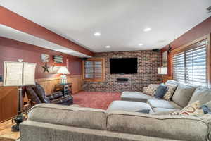Living room with brick wall, wood walls, a wainscoted wall, and recessed lighting