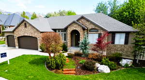 View of front facade with brick siding, an attached garage, driveway, roof with shingles, and a front yard