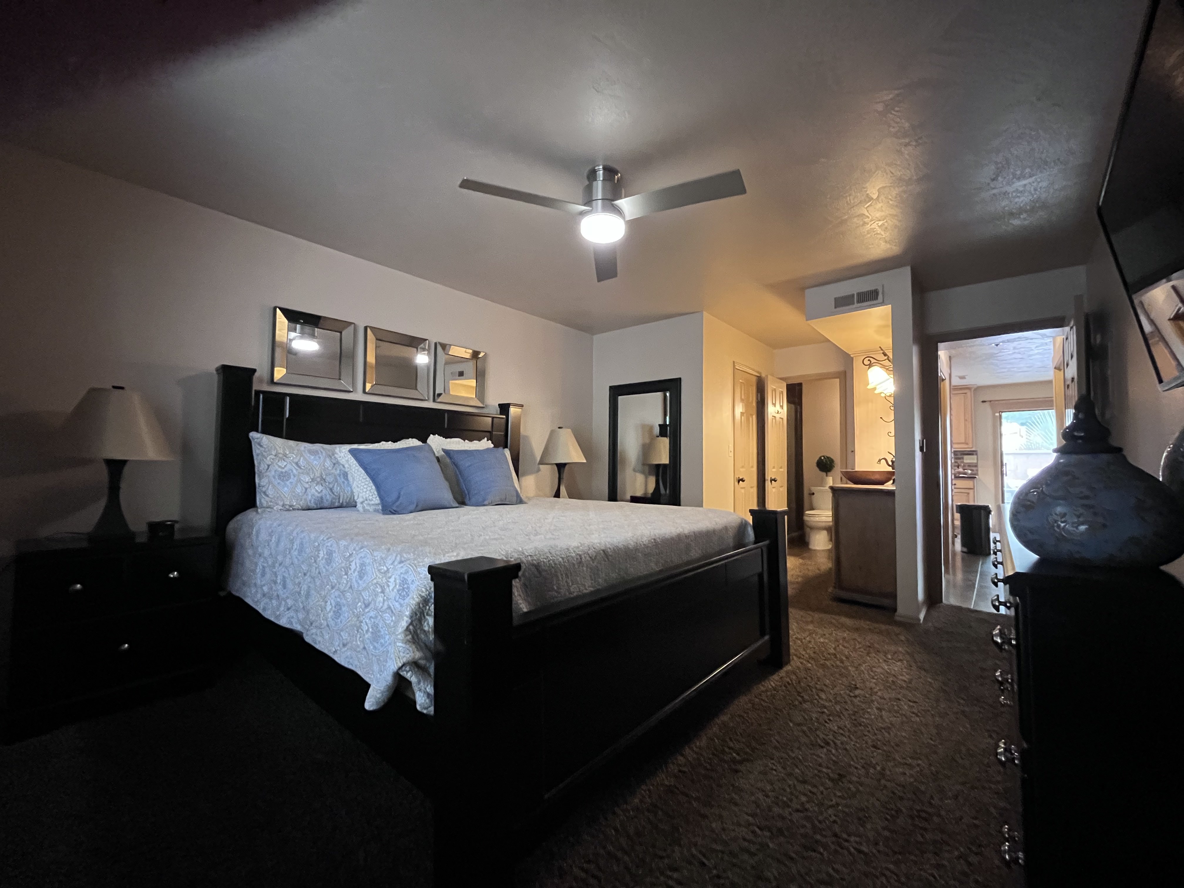 Bedroom featuring dark carpet, a ceiling fan, and connected bathroom