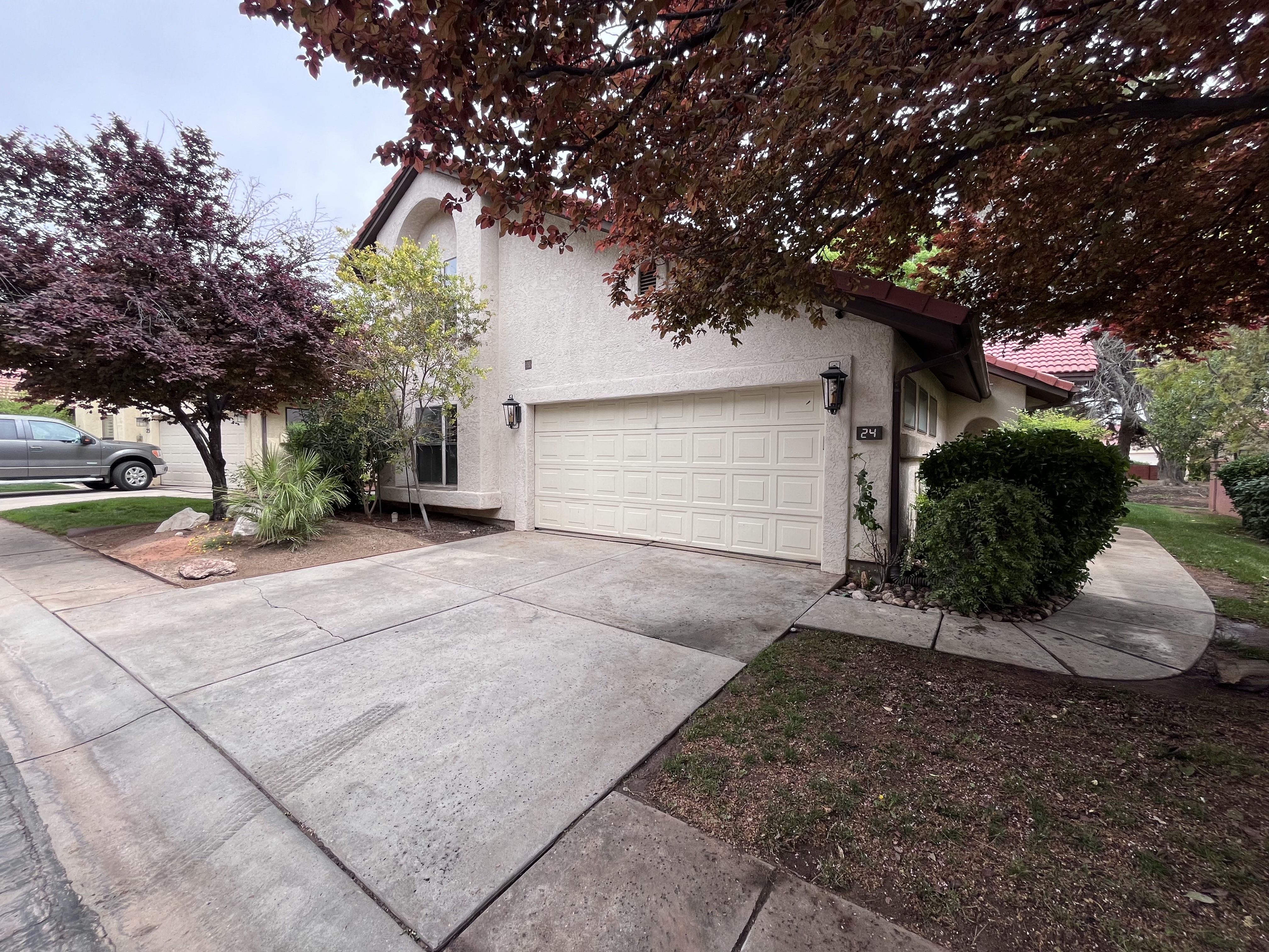 View of front of property featuring stucco siding, driveway, a garage, and a tiled roof