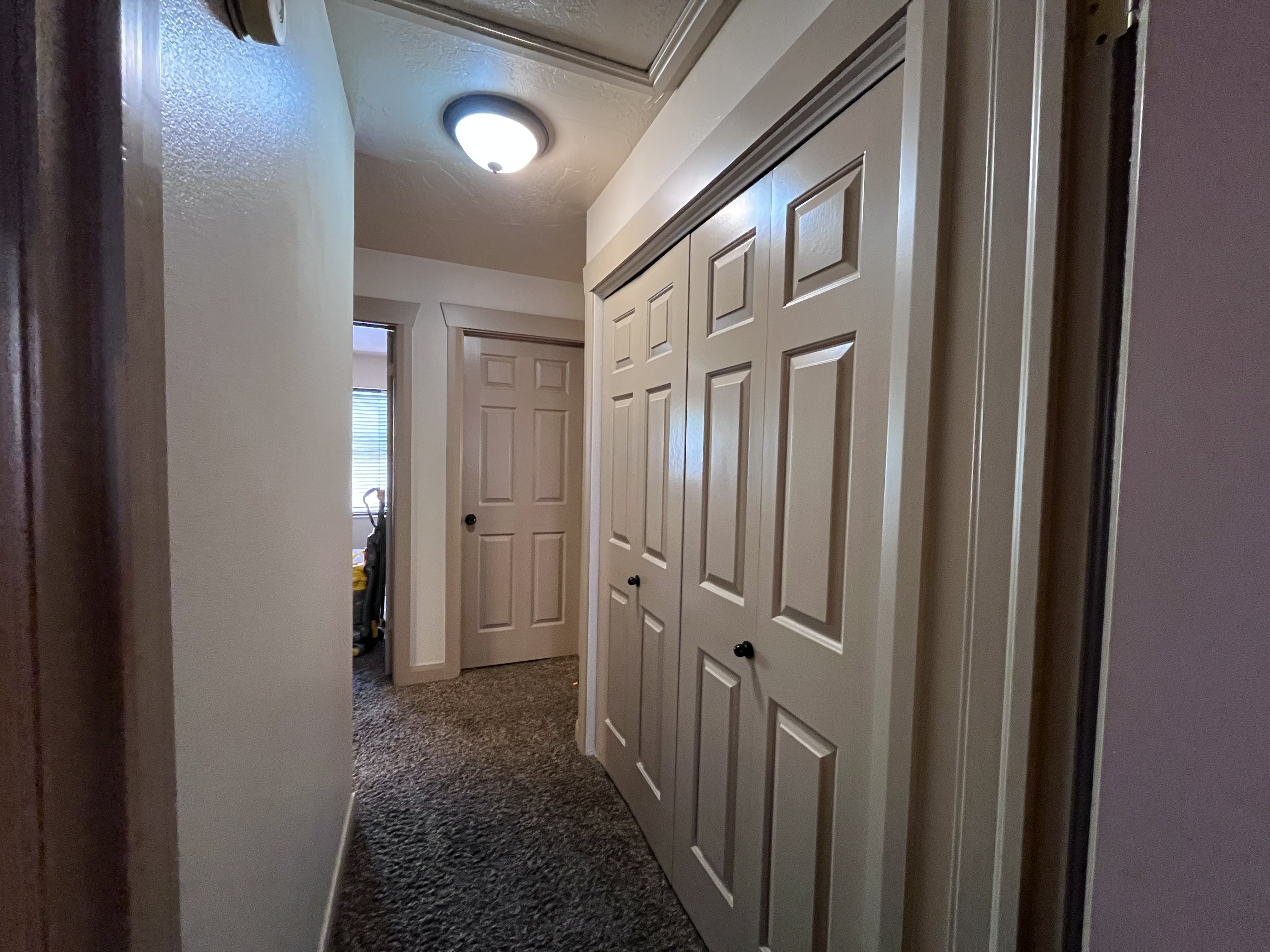 Hallway featuring dark colored carpet and a textured ceiling