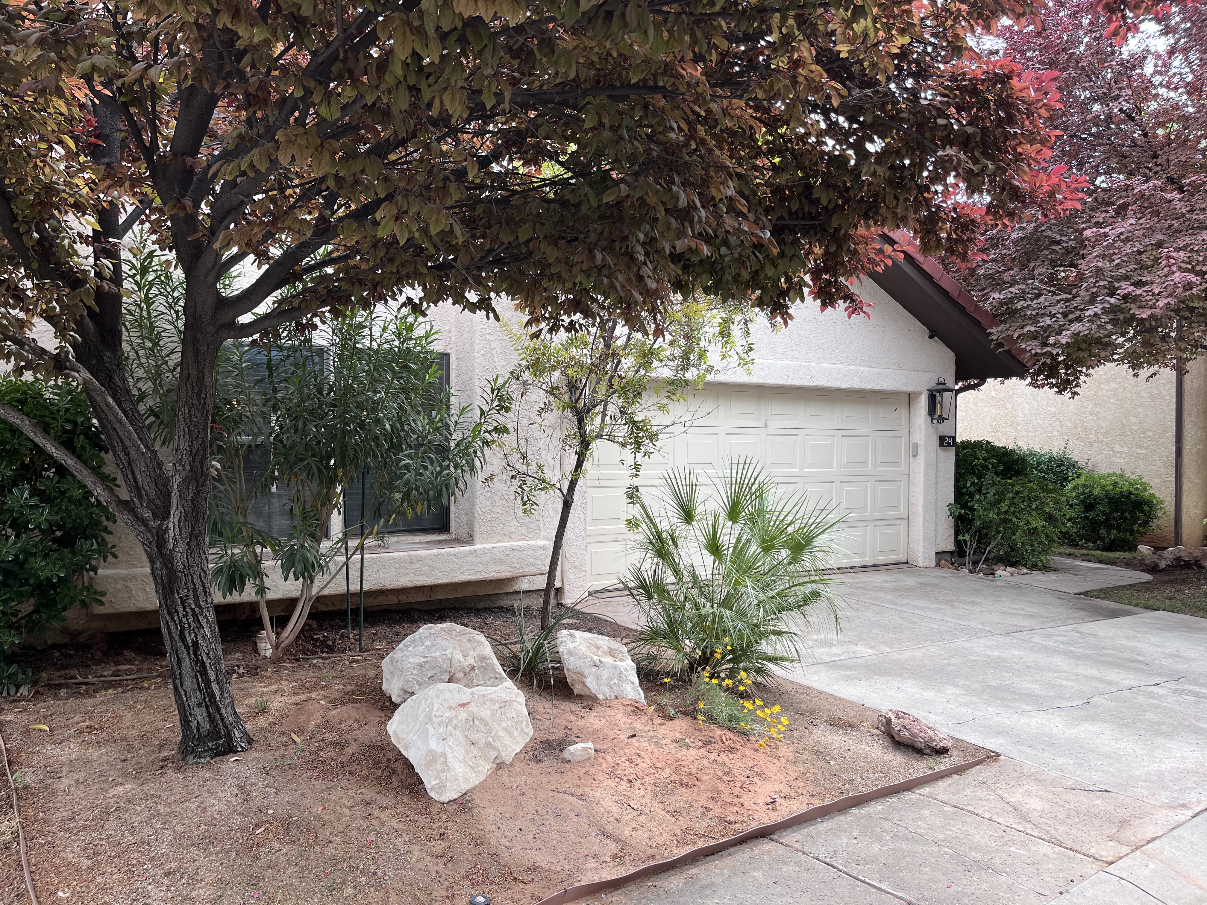View of property exterior featuring concrete driveway, stucco siding, and an attached garage