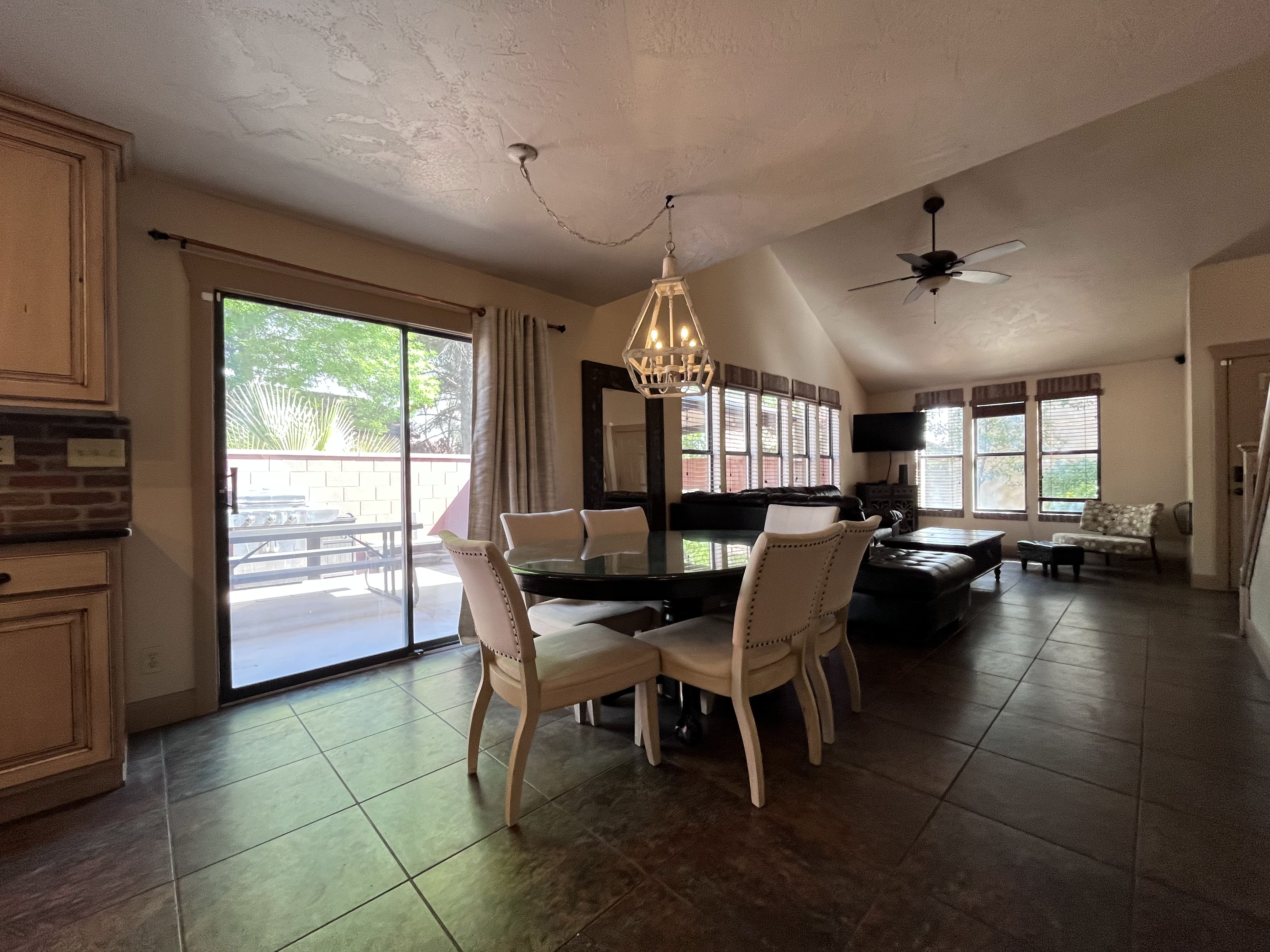 Dining space with a chandelier, a ceiling fan, plenty of natural light, dark tile patterned flooring, and lofted ceiling