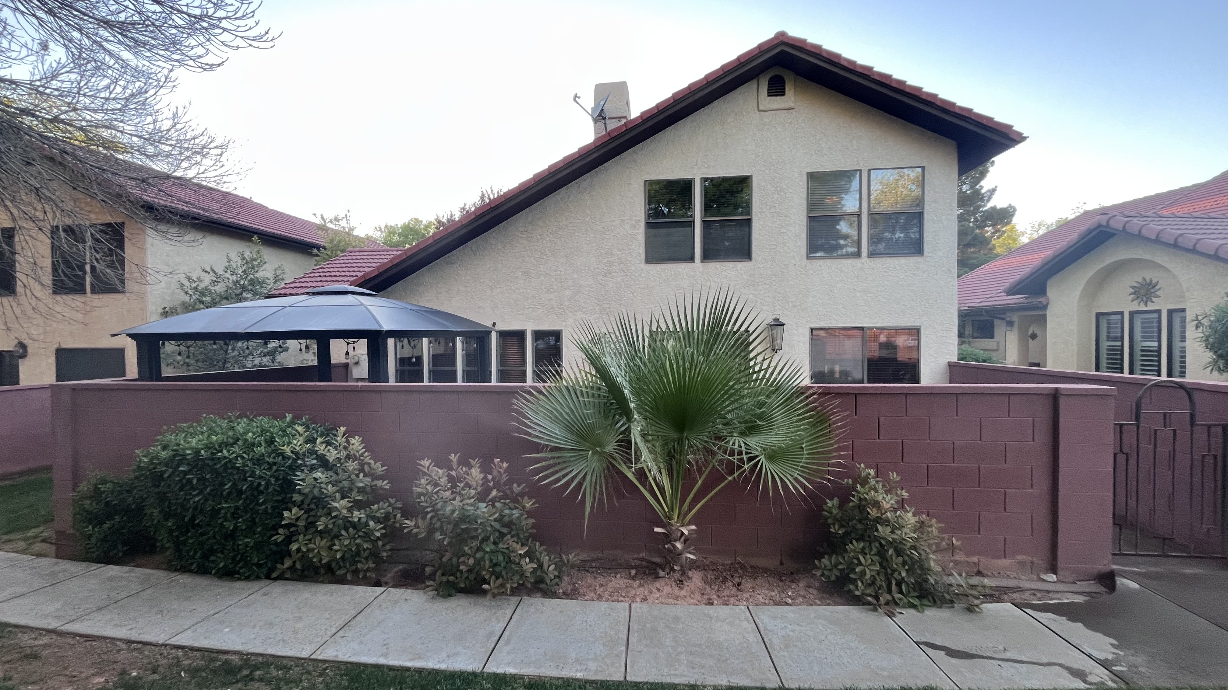 View of side of home with stucco siding, a gazebo, and a gate