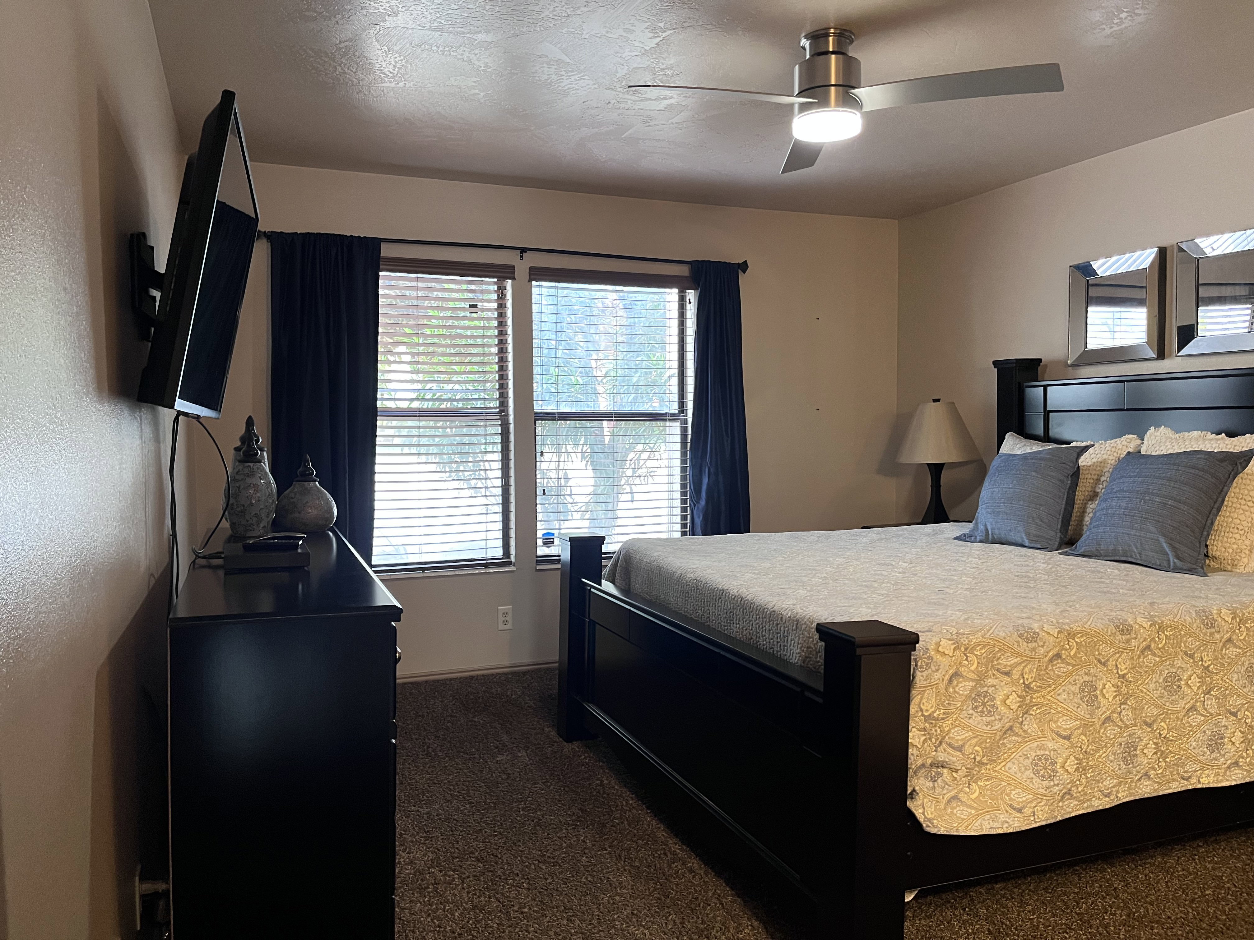 Bedroom with a ceiling fan, dark colored carpet, and a textured ceiling