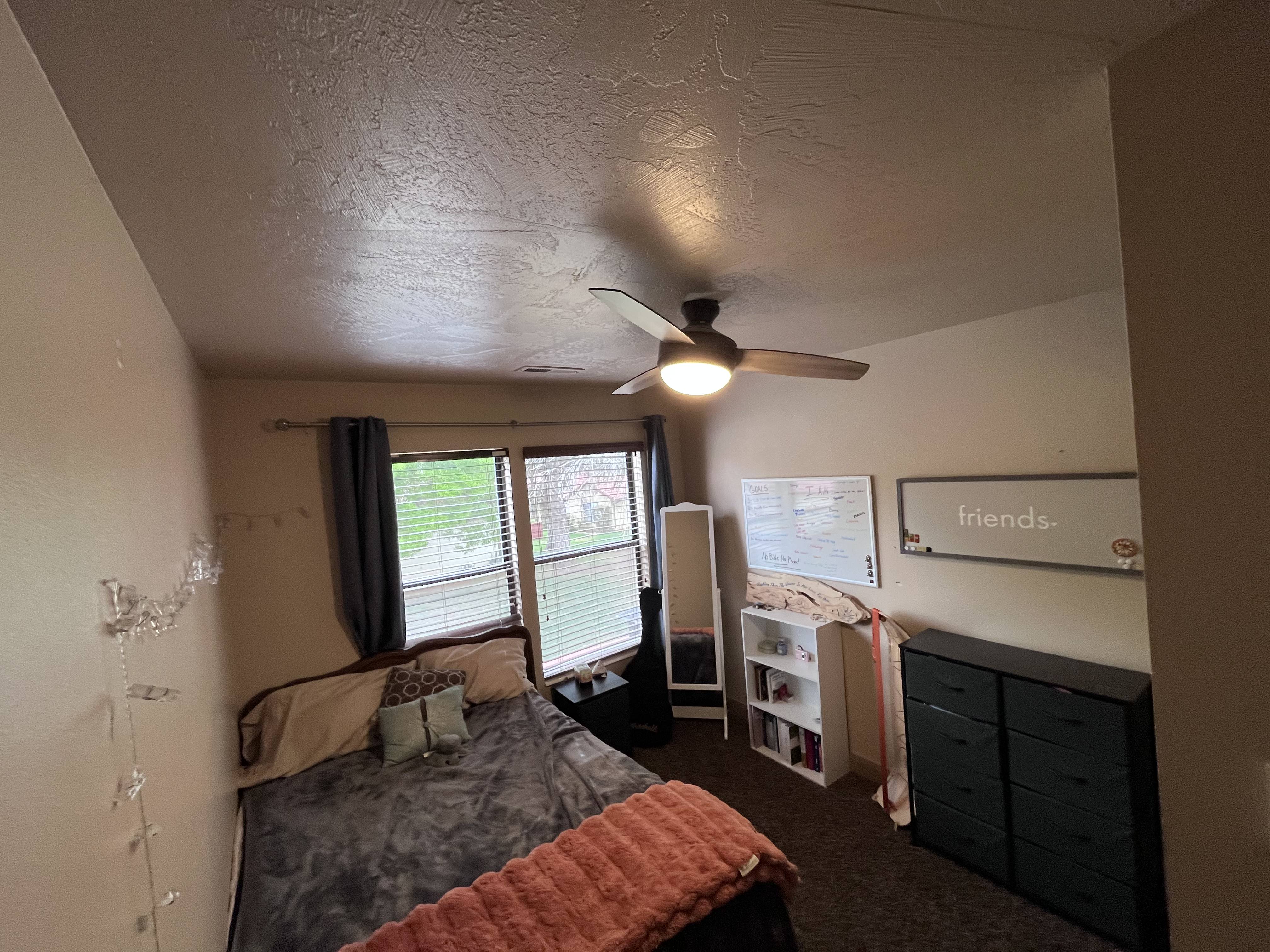 Bedroom with a ceiling fan, a textured ceiling, and dark carpet