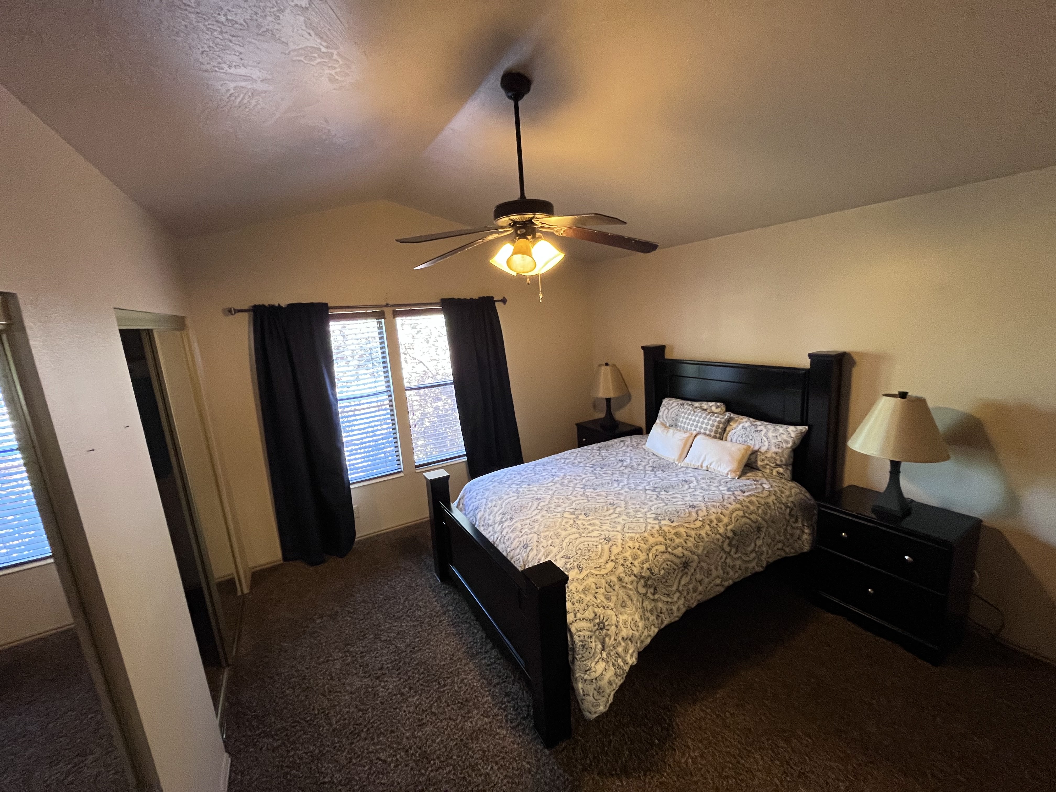 Carpeted bedroom with ceiling fan and two closets