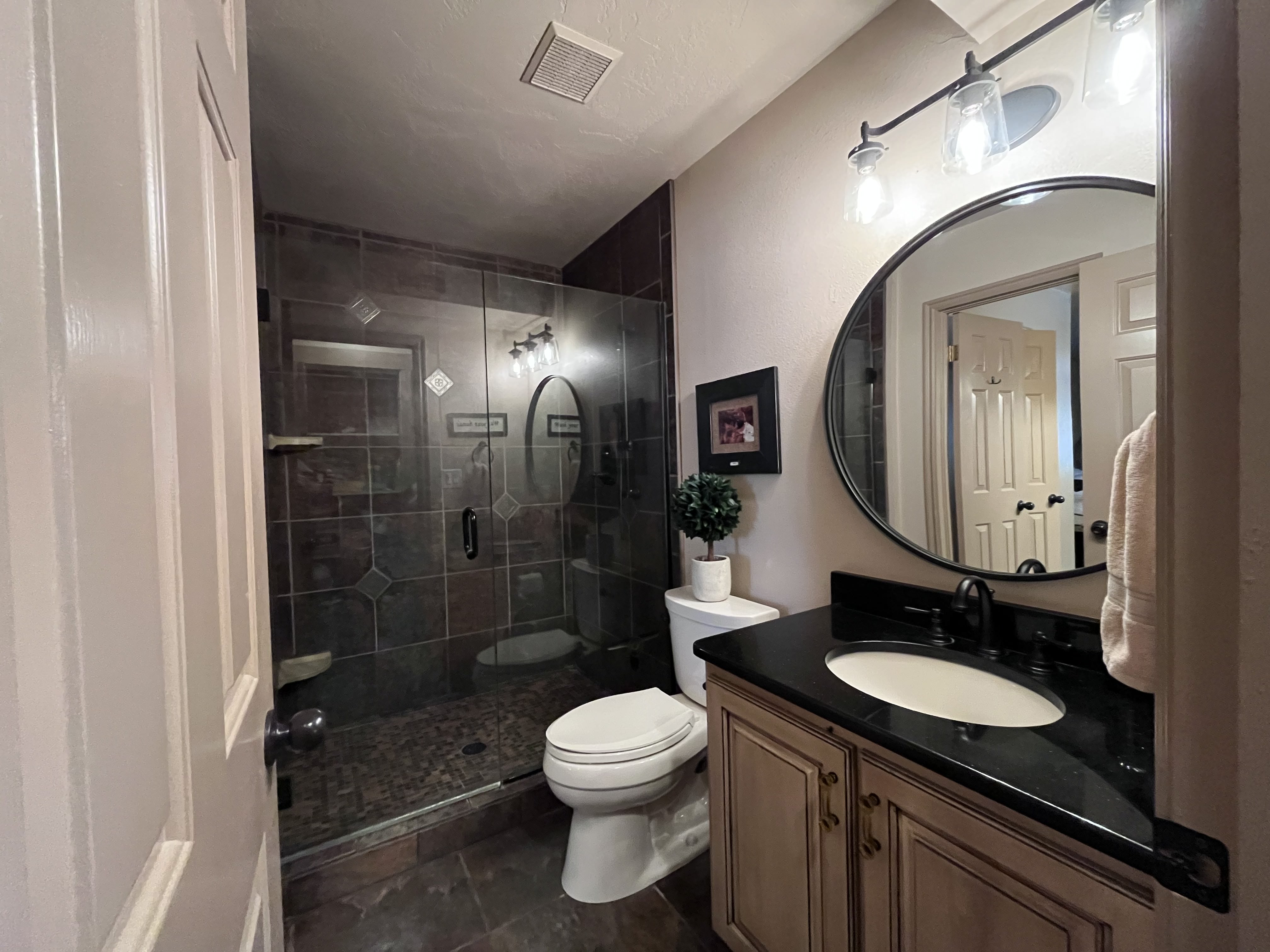 Full bathroom featuring vanity, a stall shower, and dark tile patterned floors