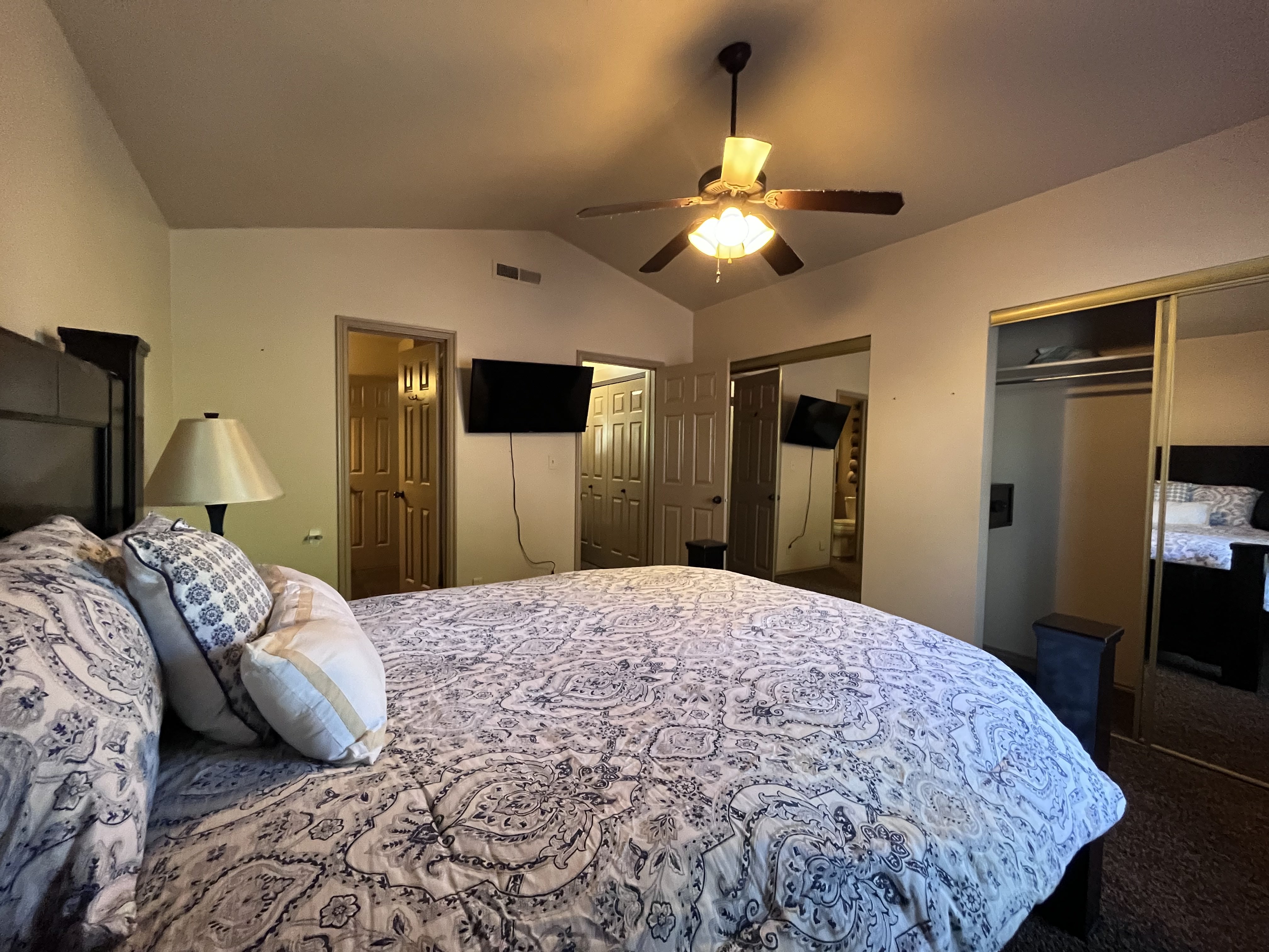 Bedroom featuring lofted ceiling, a ceiling fan, two closets, and dark carpet