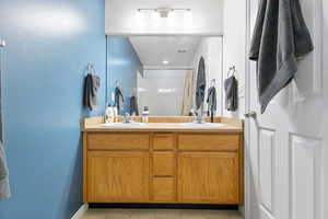 Full bath featuring double vanity, curtained shower, and light tile patterned floors