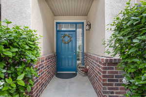 Property entrance featuring stucco siding and brick siding