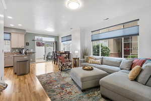 Living area featuring ornamental molding, light wood-type flooring, and recessed lighting
