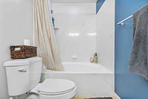 Full bath with toilet and shower / bathtub combination with curtain