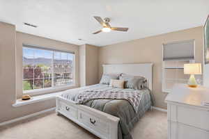 Bedroom with light colored carpet, a mountain view, and a ceiling fan