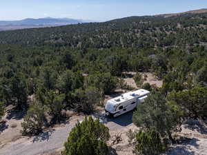 Aerial view of property and surrounding area featuring mountains and a forest