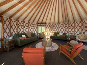 Carpeted living area featuring lofted ceiling with beams and wallpapered walls