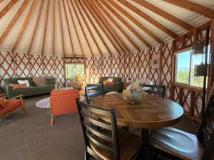 Carpeted dining room with vaulted ceiling with beams