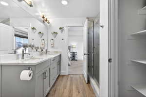 primary bedroom ensuite bathroom with double vanity, light finished floors, glass shower, linen closet, and walk in coset