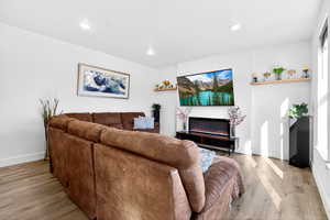 Living area with a glass covered fireplace, light wood-style floors, and recessed lighting