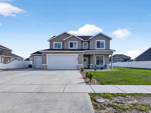 Traditional-style home with a porch, large concrete driveway, an attached garage, rv parking